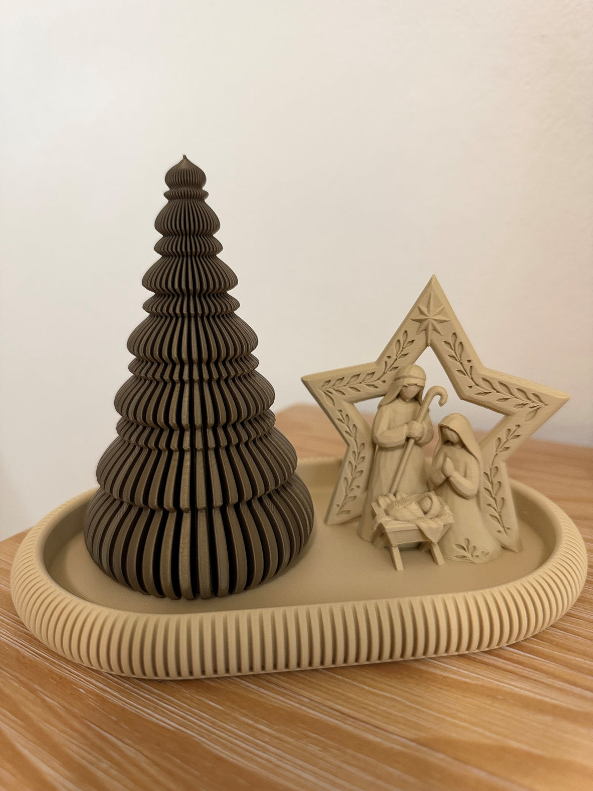 Set de decoración navideña minimalista con arbolito bronce de textura acanalada y Nacimiento beige enmarcado por una estrella, sobre bandeja Japandi ovalada con borde decorativo.